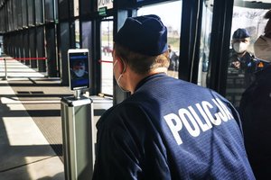 Policjant sprawdza swoją temperaturę ciała na urządzeniu - skanerze twarzy.