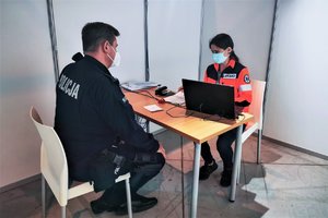 Policjant podczas rozmowy z lekarzem stanowiącej wywiad medyczny przed szczepieniem.