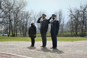 Zdjęcie kolorowe. Widoczni umundrowani policjanci przez Grobem Policjanta Polskiego na terenie KWP w Katowicach, w tym Komendant Wojewódzki Policji w Katowicach