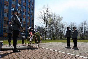 Zdjęcie kolorowe. Widoczni umundrowani policjanci przez Grobem Policjanta Polskiego na terenie KWP w Katowicach