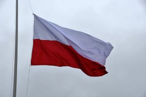 Biało czerwona flaga Polski na tle nieba, zawieszona na maszcie.
