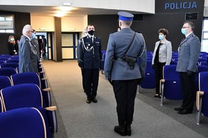 Zdjęcie kolorowe. Widoczni uczestnicy uroczystości na auli, umundurowani policjanic i kobieta w ubraniu cywilnym, widoczny m.in. Komendant Wojewódzki Policji w Katowicach