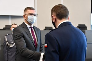 Zdjęcie kolorowe. Widoczni uczestnicy uroczystości na auli, Komendant Wojewódzki Policji w Katowicach wręcza wyróżnienie