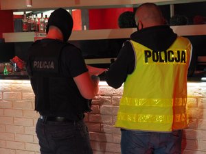 Dwóch policjantów wykonujących czynności przy barze w salonie gier