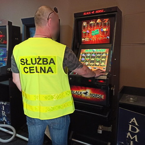Funkcjonariusz służby celnej kontroluje zabezpieczony automat do gier