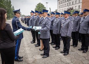 Komendant  Wojewódzki Policji w Katowicach inspektor Roman Rabsztyn wręcza akt mianowania i gratuluje funkcjonariuszowi.