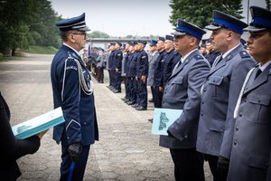 Komendant  Wojewódzki Policji w Katowicach inspektor Roman Rabsztyn wręcza akt mianowania i gratuluje funkcjonariuszowi.