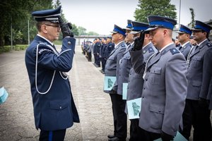 Komendant  Wojewódzki Policji w Katowicach inspektor Roman Rabsztyn wręcza akt mianowania, gratuluje funkcjonariuszowi i oddaje honor.