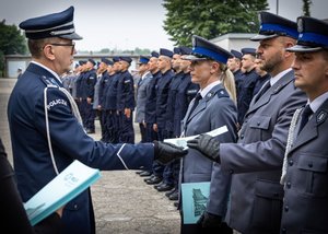 Komendant  Wojewódzki Policji w Katowicach inspektor Roman Rabsztyn wręcza akt mianowania i gratuluje funkcjonariuszowi.