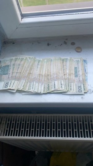 Zdjęcie kolorowe. Widocze banknoty leżące na parapecie okna