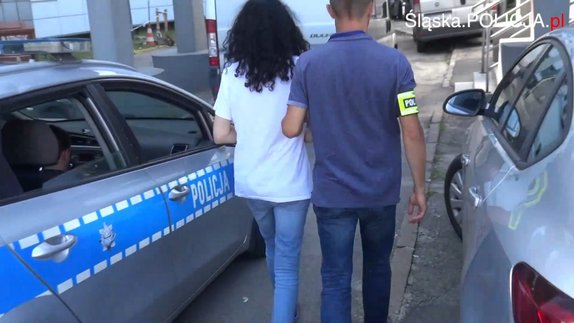 Podejrzana w kajdankach prowadzona przez policjanta w cywilu