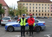 Kolorowa fotografia przedstawia policjanta wydziału ruchu drogowego wraz z ratownikiem medycznym.