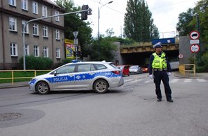 Kolorowa fotografia przedstawia policjanta wydziału ruchu drogowego kierującego ruchem.