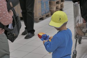 Zdjęcie kolorowe. Widoczne dzaiecko na terenie sklepu obok policjanta