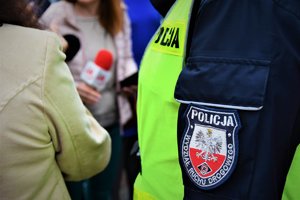 Zdjęcie kolorowe. Zbliżenie na ramie umunudrowanego policjanta z naszywką o treści: POLICJA Wydział Ruchu Drogowego