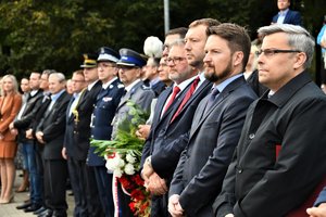 Kolorowe zdjęcie, na którym widoczni są uczestnicy uroczystości stojący w szeregu. Wśród nich Komendant Wojewódzki oraz Komendant Miejski Policji.