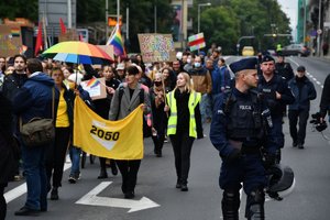 Policjanci podczas zabezpieczenia marszu. W tle jego uczestnicy.