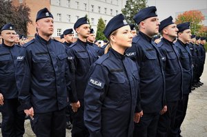 Zdjęcie kolorowe. Widoczi umunudorwani policjanci ślubujący