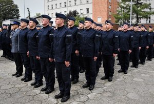 Zdjęcie kolorowe. Widoczi umunudorwani policjanci ślubujący