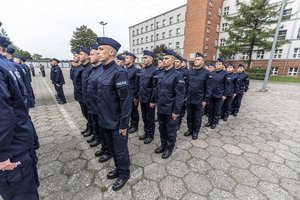 Zdjęcie kolorowe. Widoczi umunudorwani policjanci ślubujący