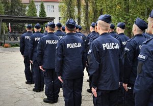 Zdjęcie kolorowe. Widoczi umunudorwani policjanci ślubujący