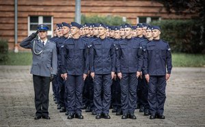 Zdjęcie kolorowe. Widoczi umunudorwani policjanci ślubujący