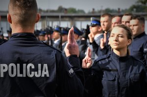 Zdjęcie kolorowe. Widoczi umunudorwani policjanci ślubujący