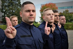 Zdjęcie kolorowe. Widoczi umunudorwani policjanci ślubujący