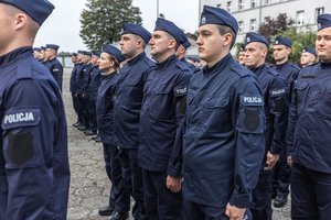 Zdjęcie kolorowe. Widoczi umunudorwani policjanci ślubujący