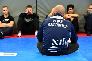 Zdjęcie kolorowe: instruktor i uczestnicy siedzą na macie ćwiczeń