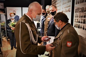 Uczestnik uroczystości gratuluje księdzu i wręcza pamiątkowy medal.