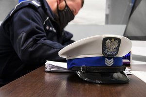 Poliucjant wypełniaq deklarację honorowego dawcy krwi. Na pierwszym planie policyjna czapka.