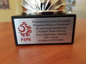Fragment pucharu z napisem Podziękowania dla Komendy Miejskiej Policji w Gliwicach za wzorową współpracę z klubem Piast Gliwice przy organizacji meczów piłki nożnej w sezonie 2020/2021.