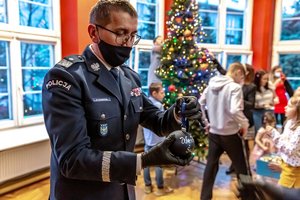 Komendant Wojewódzki Policji w Katowicach nadinsp. Roman Rabszty zawiesza świąteczną bombkę na choince.