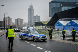 Fukncjonariusz Służby Ochorny Państwa wskazujący kierunek jazdy oznakowanemu radiowozowi policji pilotującemu kolumnę rządową