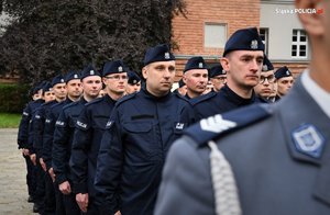 Zdjęcie kolorowe. Widoczni umudurowani policjanci na placu podczas ślubowania