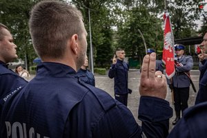 Zdjęcie kolorowe. Widoczni umudurowani policjanci na placu podczas ślubowania