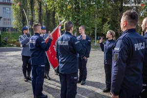 Zdjęcie kolorowe. Widoczni umudurowani policjanci na placu podczas ślubowania