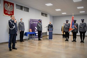Komendant Wojewódzki Policji w Katowicach podczas przemówienia, w tle kadra kierownicza śląskiej Policji oraz poczet sztandarowy.