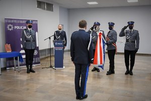 Komendant Wojewódzki Policji w Katowicach stoi przed policyjnym pocztem sztandarowym, policjanci oddają honor Generałowi.