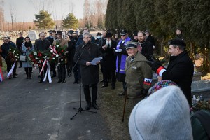 Widoczni uczestnicy uroczystości, mundurowi i cywile na terenie cmentarza