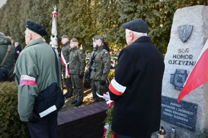 Widoczni uczestnicy uroczystości, mundurowi i cywile na terenie cmentarza