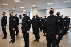 Zdjęcie kolorowe. Widoczni umundurowani policjanci biorący udział w uroczystym ślubowaniu nowych mundurowych.