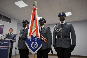 Zdjęcie kolorowe. Widoczni umundurowani policjanci biorący udział w uroczystym ślubowaniu nowych mundurowych.