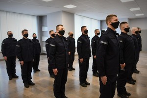 Zdjęcie kolorowe. Widoczni umundurowani policjanci biorący udział w uroczystym ślubowaniu nowych mundurowych.