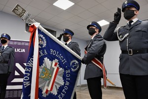 Zdjęcie kolorowe. Widoczni umundurowani policjanci biorący udział w uroczystym ślubowaniu nowych mundurowych.