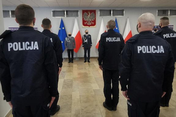 Zdjęcie kolorowe. Widoczni umundurowani policjanci biorący udział w uroczystym ślubowaniu nowych mundurowych.