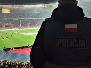 Zdjęcie kolorowe. Widoczny policjant na terenie stadionu
