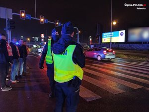 Zdjęcie kolorowe. Widoczne policyjne radiowozy i policjanci na terenie Katowic