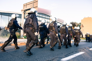 Widoczni umunudrowani policjanci i radiowozy oraz kibice w drodze na mecz